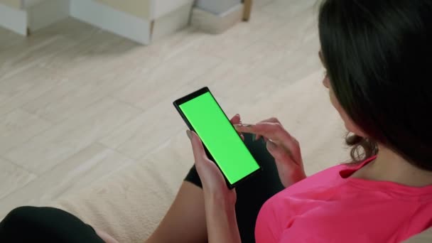 Зворотній перегляд жінки, що тримає смартфон із зеленим екраном, який дивиться вміст, торкається або прочиняється. Вид зверху — стокове відео