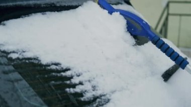 Kadın elleri, kar arabasını fırçayla temizler. Kar yağışı arabayı kapladı. Yavaş çekim