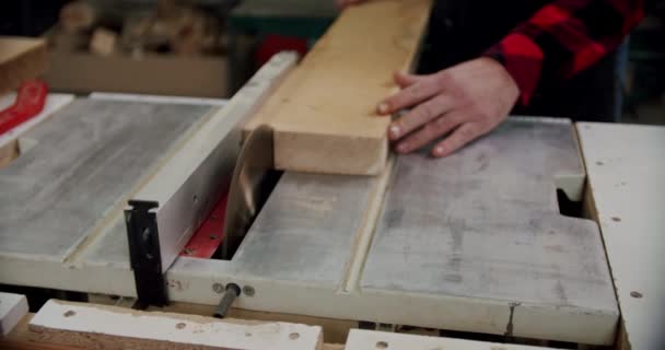 In der holzbearbeitenden Werkstatt eines kleinen Möbelherstellers schneidet der Meister mit der Kreissäge eine Holzplatte. Zeitlupe. Nahaufnahme — Stockvideo