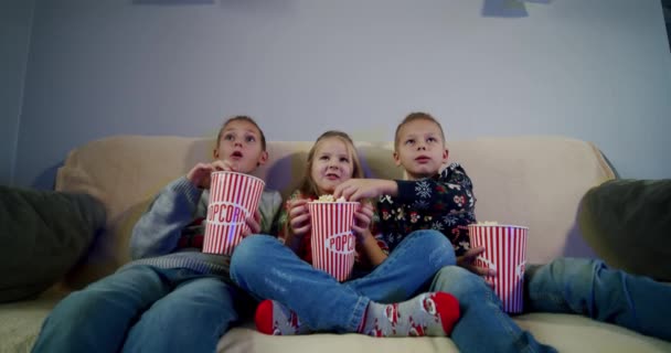 Grupo de crianças assistindo filme na TV à noite em casa e comer pipocas. V3 — Vídeo de Stock