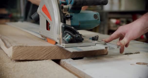 Au ralenti. Le maître découpe une planche de bois avec une scie circulaire dans l'atelier de menuiserie d'un petit fabricant de meubles. V4 — Video