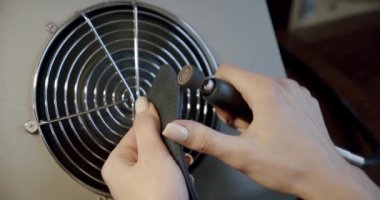 Genç deri kadın işçi atölyesinde üretim sırasında deri kemerin kenarını yakıyor. Kapatın. Yavaş çekim V4