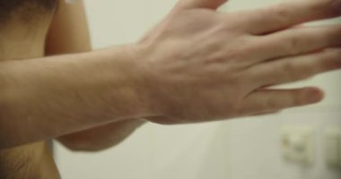 Yakın çekim, banyoda bir adam eline sabun ya da krema sıkar..