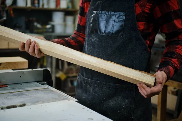 Un trabajador sostiene una tabla de cortar en un taller de madera. De cerca. —  Fotos de Stock