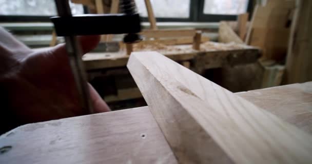 Houtbewerker fixeert het hout met een klemhoutsnijgereedschap uit houtkrullen, Close up — Stockvideo