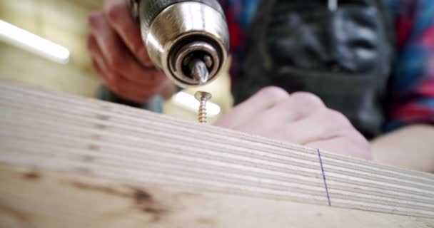 Cose up Arbeiter in einer Holzbearbeitungshalle mit einem Bohren in Holz mit Schraube an Ort und Stelle gedreht. — Stockvideo