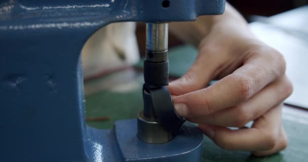 Împușcat aproape de specialist care lucrează cu piele, mâinile de sex feminin instalează nituri pe un produs din piele. Close up — Videoclip de stoc