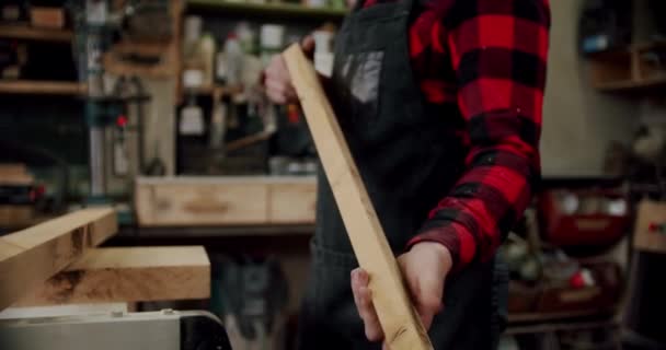 Közelről. A mester feldarabol egy fából készült munkást, fog egy deszkát, és berakja a gépbe. Lassú mozgás.. — Stock videók