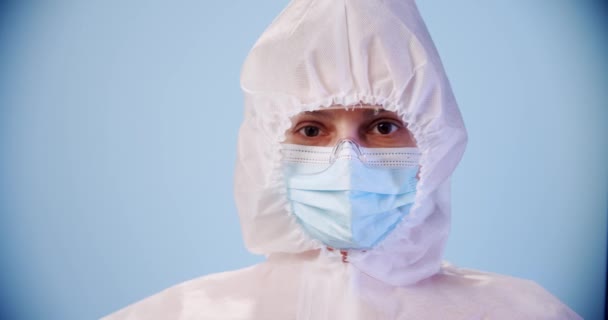 Médecin ou infirmière bleui portant un équipement de protection individuelle et tenant une seringue du vaccin corona covid-19 en laboratoire ou à l'hôpital sur fond bleu — Video