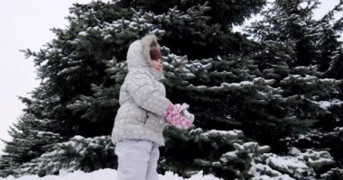 Ağır çekim. Küçük kız sokağa kar fırlatıyor.