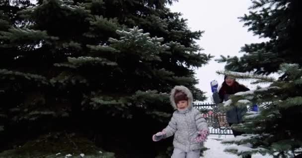 . Niños sonrientes y alegres juegan bolas de nieve en la calle, corren y lanzan bolas de nieve en cámara lenta — Vídeo de stock