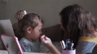 Küçük kız makyaj fırçasıyla oynuyor ve arkadaşına nasıl makyaj yaptığını hayal ediyor. geniş çekim
