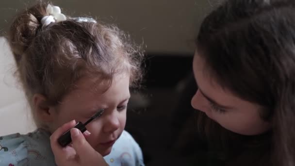 Dziewczynka bawi się pędzlem do makijażu i wyobraża sobie, jak robi makijaż swojemu przyjacielowi. Zbliżenie strzału — Wideo stockowe