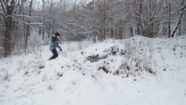 Powolny ruch Młoda piękna biała dziewczyna i pies biegający razem w śnieżny dzień. W lesie. — Wideo stockowe