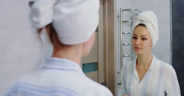 Close up de mulher atraente colocando maquiagem com escova adicionando rímel no olho e olha no espelho no banheiro — Vídeo de Stock
