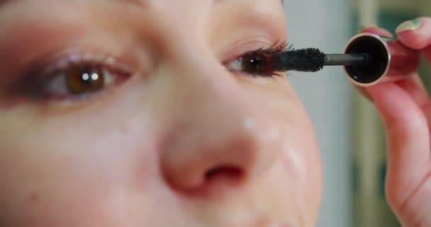 Close-up van aantrekkelijke vrouw zetten op make-up met borstel toe te voegen mascara op oog. — Stockvideo