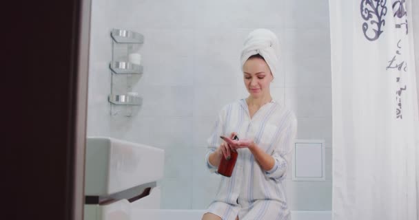 Закройте руку женщины нанося крем для тела и запах лосьона крем на руку в ванной комнате — стоковое видео