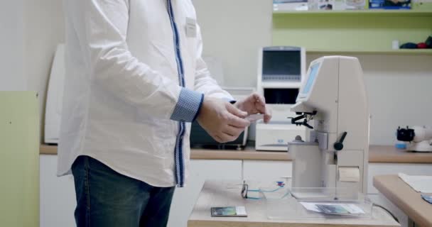 Haciendo la tienda de gafas, el oftalmólogo pone la lente en la máquina para centrar. — Vídeos de Stock