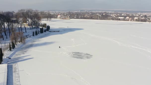 Il pescatore sta pescando da solo sul fiume ghiacciato. Concetto pesca invernale. Vista aerea drone — Video Stock