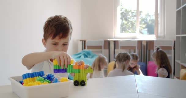 Los niños juegan con bloques coloridos de juguetes educativos en la guardería o preescolar. juguetes. — Vídeo de stock