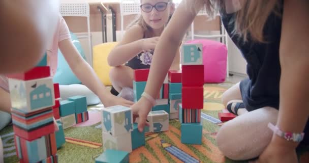 미취학 아동들은 나무 블록을 만드는 것을 돕고 있습니다. 함께 바닥 카펫에 앉아 있죠. 닫아 — 비디오