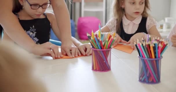 Τα παιδιά φτιάχνουν διαφορετικά σχήματα από χαρτί με τη βοήθεια ενός δασκάλου.. — Αρχείο Βίντεο