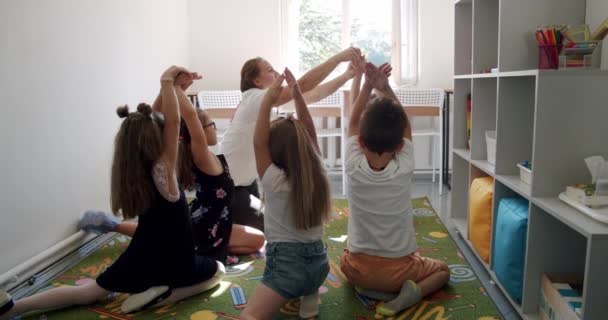 Pozitif genç öğretmen, hafif oturma odasında parmakları geliştirme egzersizleri yapıyor. Sürüm 4 — Stok video