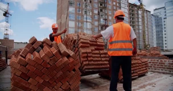 Stavební dělníci připevňují materiál k jeřábu. Široký záběr — Stock video