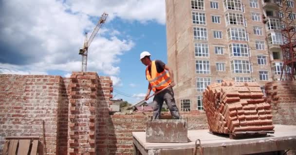 Homme travailleur pose la brique dans le mur avec du ciment à l'aide de truelle. Vercion 3 — Video