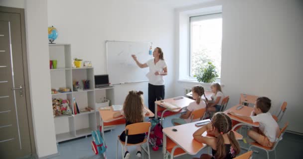 Sınıftaki çocuklar, öğretmen tahtada açıklıyor.. — Stok video