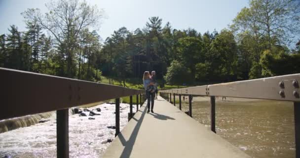 Mutter mit Kind im Arm geht über die Brücke. — Stockvideo