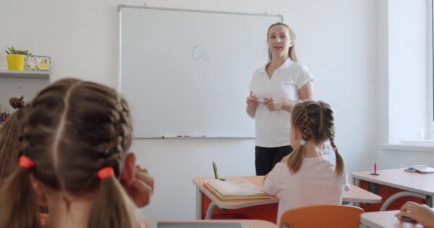 Okul çocukları sınıfta sıralarında oturup öğretmenlerini dinliyorlar.. — Stok video