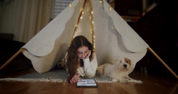 Frau liegt mit Hund Jack Russell auf dem Boden und benutzt Tablette. Urteil 4 — Stockvideo