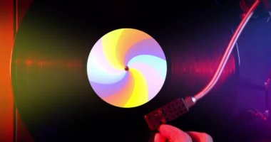 Siyah vinil plak dönüyor ve renkli etiketli DJ pikabında müzik çalıyor. Üst görüntüden vinil diske kırmızı ışıkta. Sürüm 4