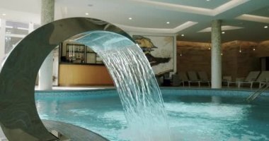 Kapalı yüzme havuzunda güneşli yataklar ve duş havuzu. Kamerayı taşı