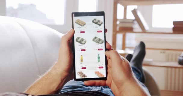 Mand at Home Liggende på sofa ordrer Sushi I blured Online Store ved hjælp af levering app på en Smartphone. Fødested – Stock-video