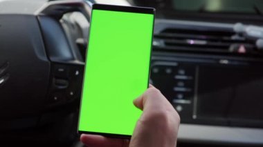 Arabadaki sürücünün elini kapat. Bir arabanın içinde yeşil ekranlı akıllı telefon kullan..