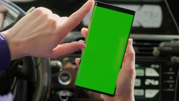 車の中でドライバーの女性の手を閉じる車の中で、緑の画面を持つスマートフォンを使用しています。第二版 — ストック動画