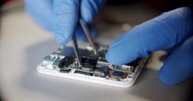Elektronik tamir servisindeki tamirci, özel aletlerin yardımıyla telefonu tamir ya da teşhis için söker.