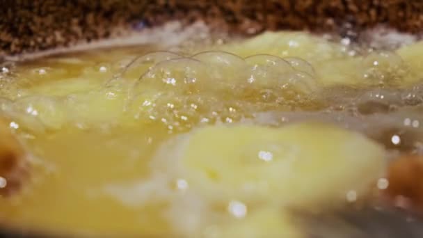 Faire frire les beignets faits maison sur l'huile bouillante chaude, préparation de la malbouffe grasse. Vue rapprochée des beignets Version 3 — Video
