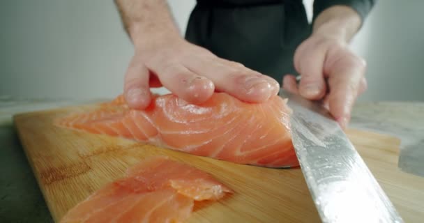 Chef begins to cut with a knife fish to the wooden board. Close up, Slow motion Version 2 — Stock Video