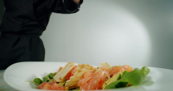 Mani di chef cospargere di spezie e condimenti insalata verde di pomodori e foglie fresche, pesce rosso. Chiudete. Versione al rallentatore 2 — Video Stock