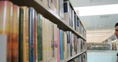 Kütüphanede bir üniversite öğrencisi var ve bir kitap seçiyor..