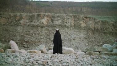Geleneksel başörtüsü takan çekici Müslüman kız. Taşlı bir yolda duruyor..