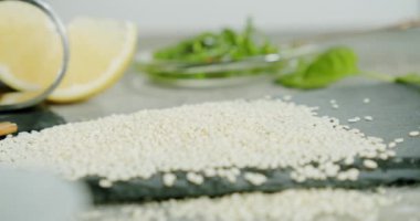 İnsan parmaklarını kapatın. Masadan beyaz susam tohumları alın.