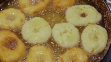 Ev yapımı donutları kızgın yağda kızartmak, abur cubur hazırlamak. Çöreklerin en üst görüntüsü. Yavaş çekim