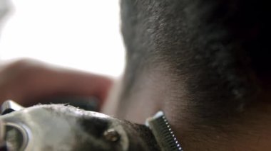 Berberin yakın çekimi genç adamın saçını saç makasıyla kesiyor. Yavaş çekim görünümü