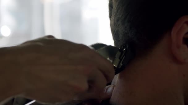 Close-up van de kapper knipt de jonge mannen haar met behulp van een tondeuse. Slow motion uitval — Stockvideo