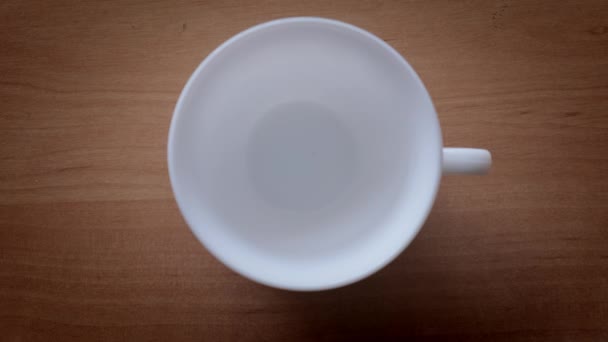 Los gránulos de café instantáneo se vierten en una taza blanca. cámara lenta, Vista superior — Vídeo de stock