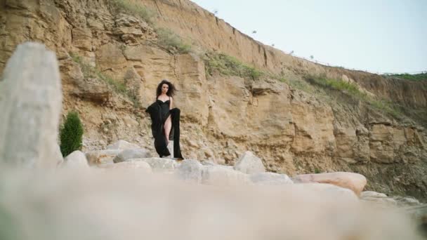Długie włosy kobieta w czarnym stroju kąpielowym idzie na wieczorną pustynię i rock. Zwolniony ruch — Wideo stockowe